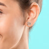 Close-up of an ear wearing a silver earring with a turquoise background