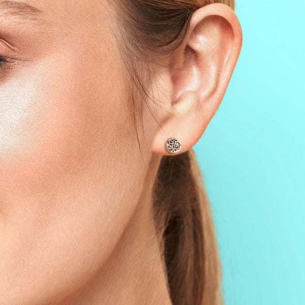 Close-up of an ear wearing a decorative earring against a light blue background
