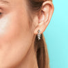 Silver fish skeleton earring worn by a person with a light blue background