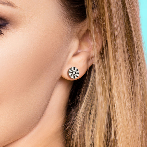 Close-up of a woman wearing a silver earring with a black design.