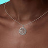 Silver necklace with a intricate pendant on a person's neck against a blue background
