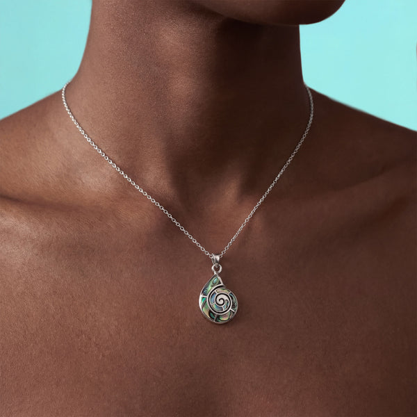 Necklace with a spiral pendant on a person against a teal background