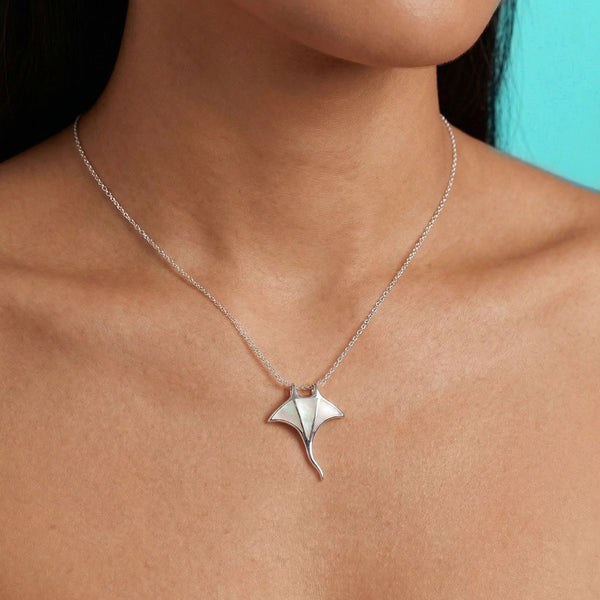 Silver necklace with a pendant worn by a person against a turquoise background